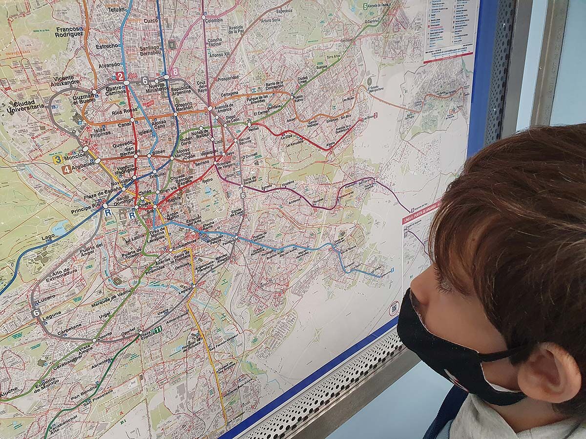 Nico estudiando de cerca el plano completo de la red de metro de Madrid colgado en la pared de un vagón