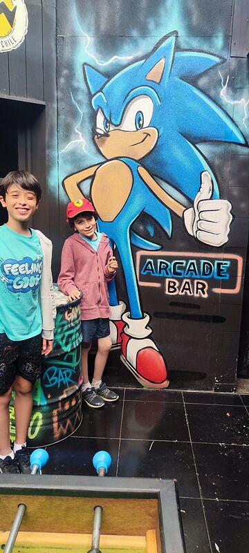 Nico y Bruno delante de un mural de Sonic en la entrada de un Arcade Bar de Santiago