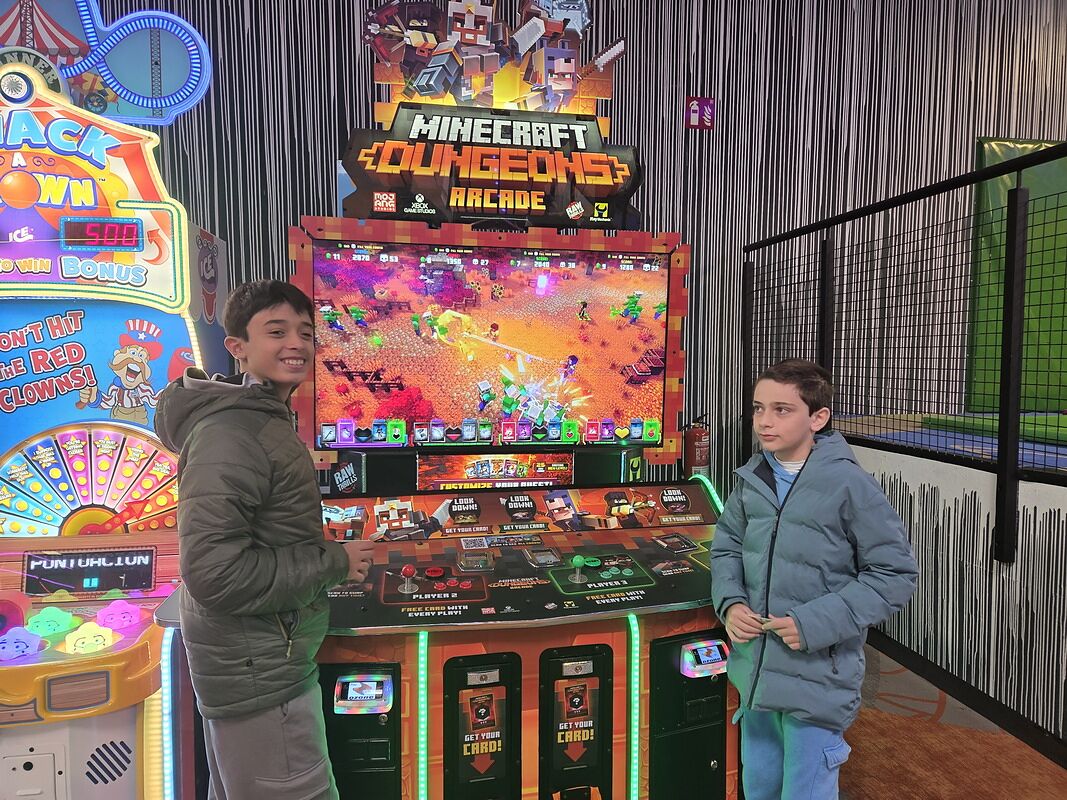 Nico y Bruno delante de una máquina arcade de Minecraft Dungeons en Córdoba
