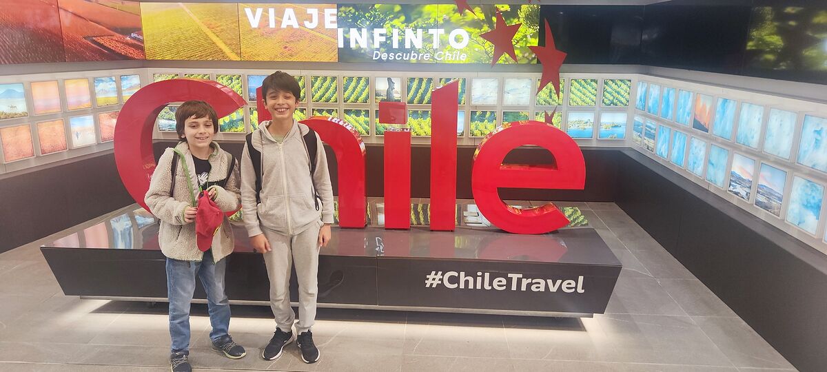 Nico y Bruno delante de las letras rojas gigantes de Chile en el aeropuerto de Santiago