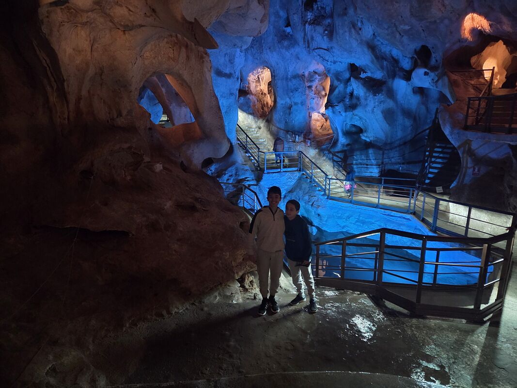 Nico y Bruno dentro de las Cuevas del Tesoro de Málaga, iluminadas de azul