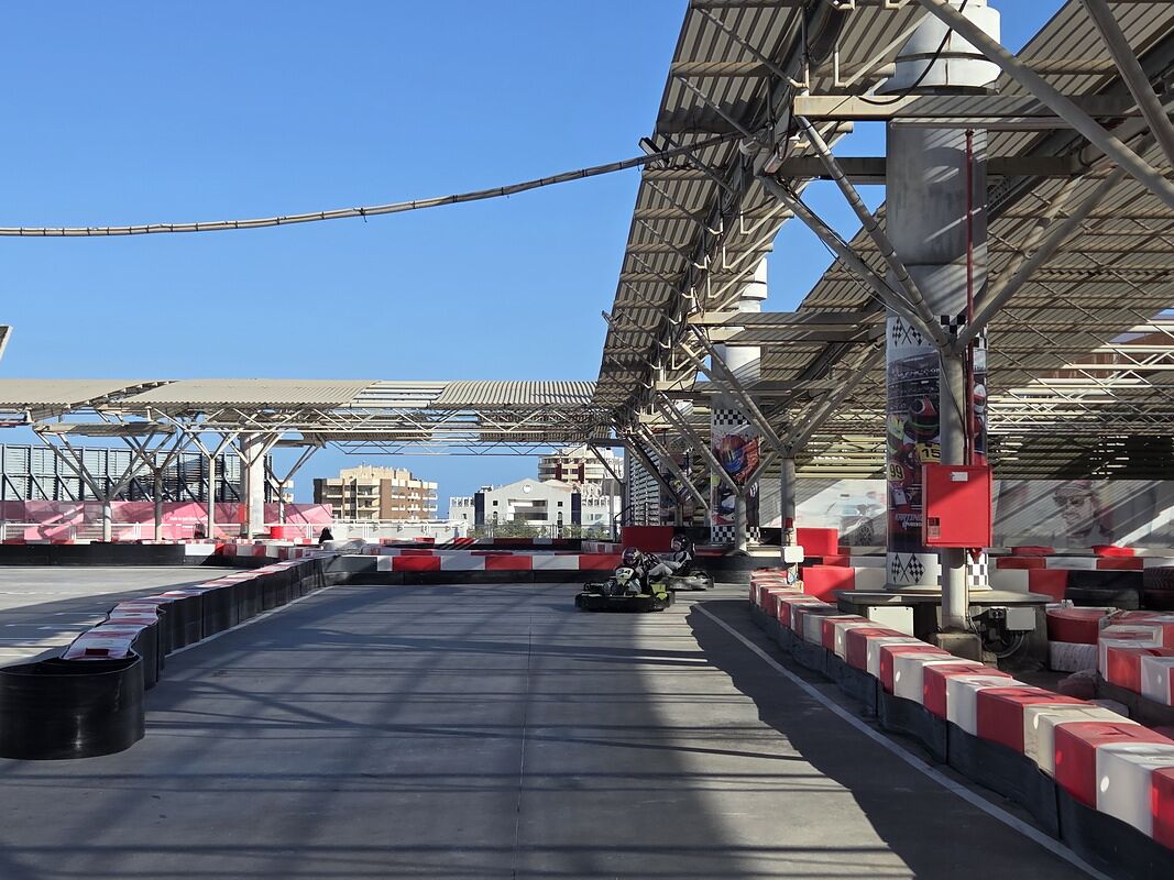 Circuito de karts con barreras rojas y blancas y un kart en la recta