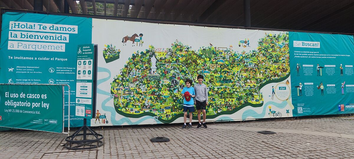 Nico y Bruno delante del mural con el mapa ilustrado del Parquemet, el parque metropolitano de Santiago