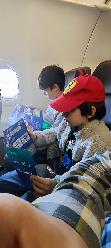 Nico y Bruno sentados en el avión leyendo la tarjeta de seguridad del A321