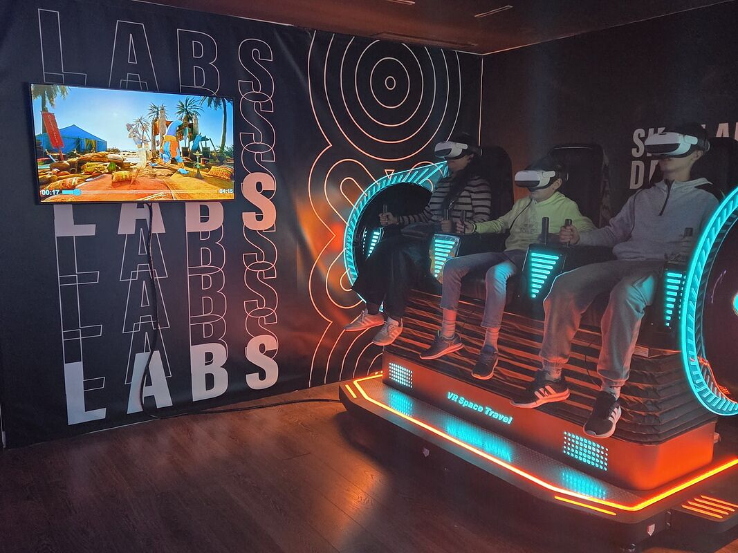 Tres personas con gafas de realidad virtual sentadas en unos asientos que se mueven, en el Museo del Videojuego de Málaga